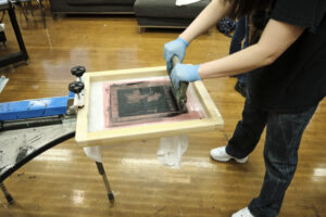 A student screen prints a shirt with the words "Lady Day" and a woman singing