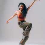 A photo of Adri, a Mexican woman with long curly hair, balancing on one foot with her arms spread out.