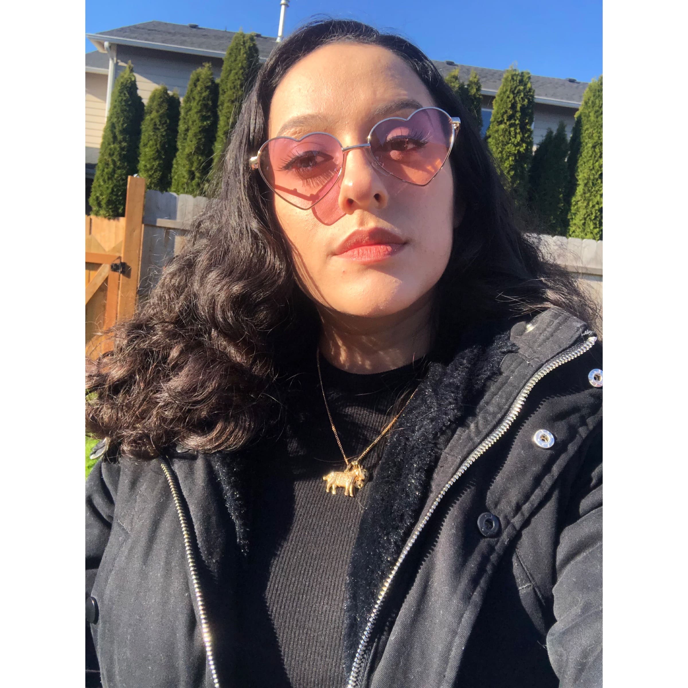 Headshot of Cecelia DeLeon, a Chicana woman with curly black hair wearing heart-shaped sunglasses