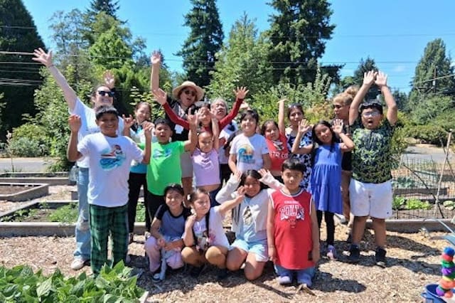 Group photo of students in a garden, with their arms up in excitement
