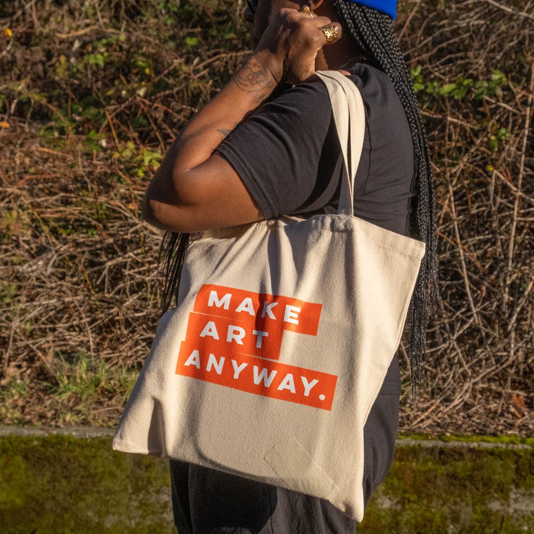 Photo of a shoulder of a tote bag on a shoulder, with the arm holding the top of the bag.